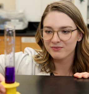 Kayla Ward, chemistry major, looks at vile of purple liquid