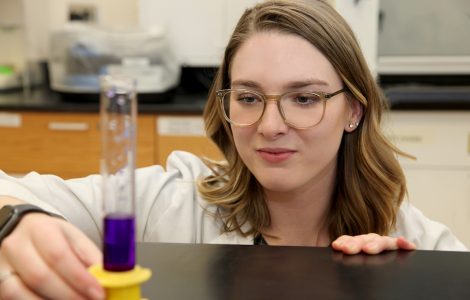 Kayla Ward, chemistry major, looks at vile of purple liquid