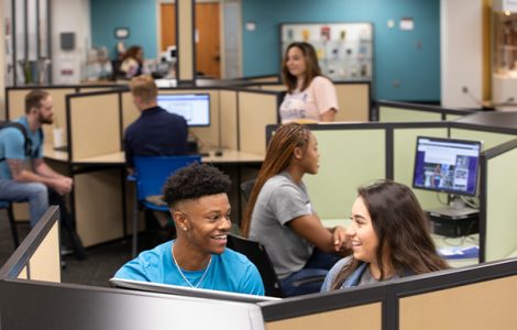 Male and female student working on computer in library