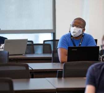 Students wearing a mask sitting in a cybersecurity classroom