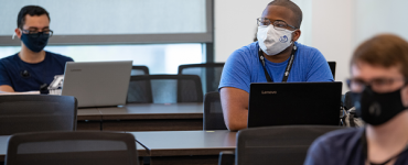 Students wearing a mask sitting in a cybersecurity classroom