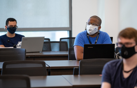 Students wearing a mask sitting in a cybersecurity classroom